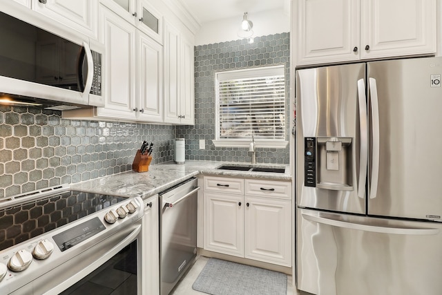 kitchen featuring decorative backsplash, white cabinets, light stone countertops, sink, and stainless steel appliances