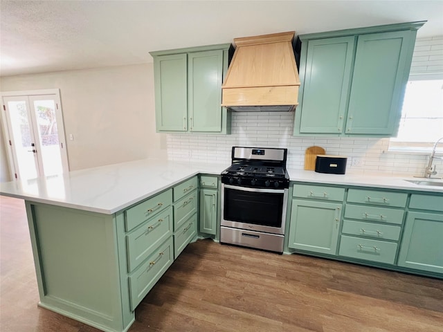 kitchen featuring stainless steel range, custom range hood, green cabinets, and kitchen peninsula