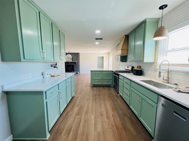 kitchen with wood-type flooring, gas range, dishwasher, decorative light fixtures, and green cabinetry