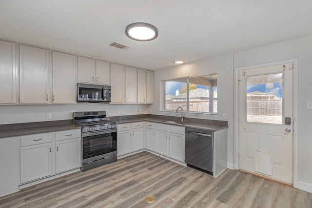 kitchen with light wood-type flooring, appliances with stainless steel finishes, sink, and white cabinets