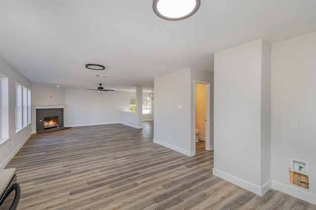 unfurnished living room featuring wood-type flooring, ceiling fan, and a fireplace