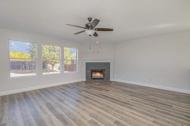 unfurnished living room featuring ceiling fan, a fireplace, and light hardwood / wood-style flooring