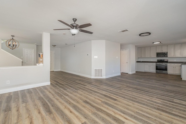 unfurnished living room featuring ceiling fan with notable chandelier and wood-type flooring