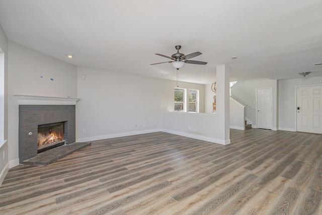 unfurnished living room featuring ceiling fan, hardwood / wood-style floors, and a brick fireplace