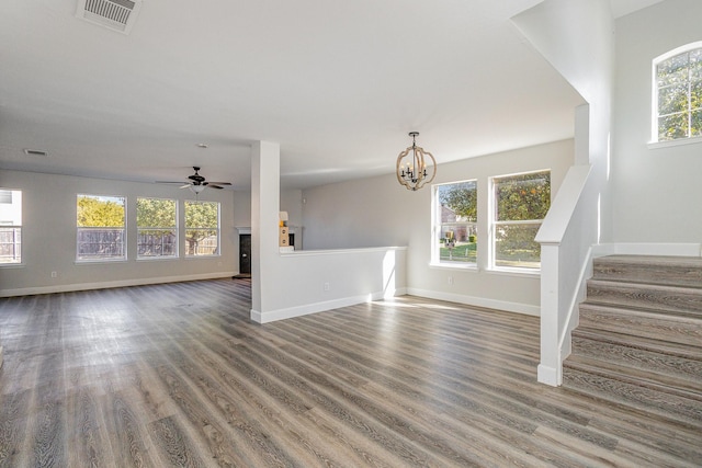 unfurnished living room featuring wood-type flooring, plenty of natural light, and ceiling fan with notable chandelier