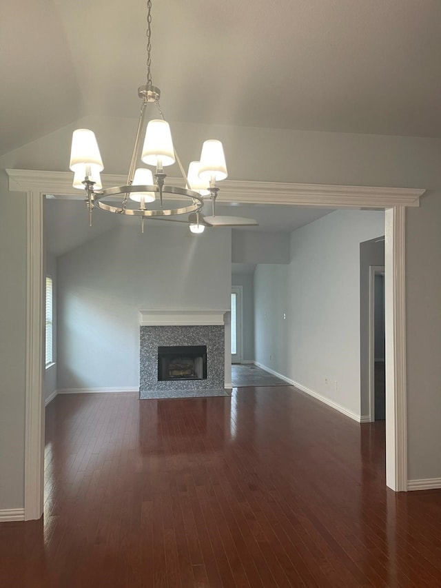 unfurnished living room with an inviting chandelier, lofted ceiling, a fireplace, and dark hardwood / wood-style flooring