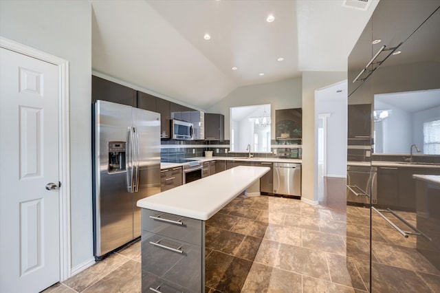 kitchen with lofted ceiling, decorative backsplash, a kitchen island, stainless steel appliances, and sink