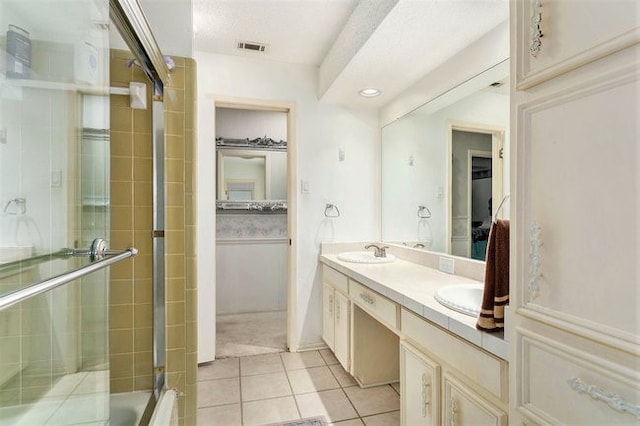 bathroom featuring vanity, a textured ceiling, tile patterned floors, and shower / bath combination with glass door