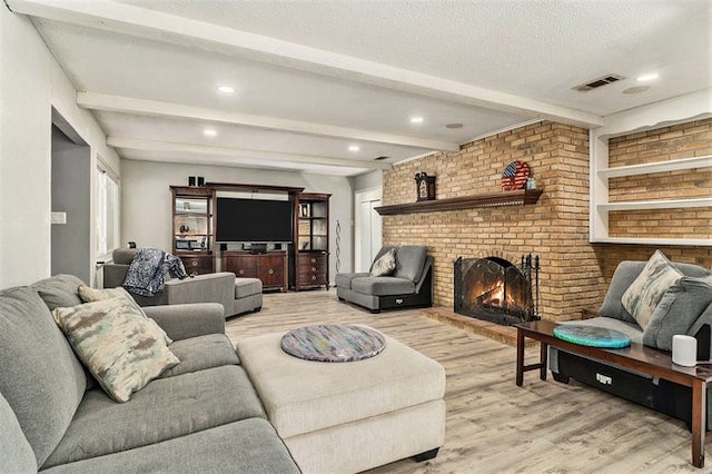 living room featuring beam ceiling, a textured ceiling, light wood-type flooring, and a fireplace