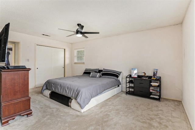 bedroom featuring a closet, light colored carpet, and ceiling fan