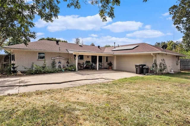 rear view of property featuring a patio, a lawn, and solar panels