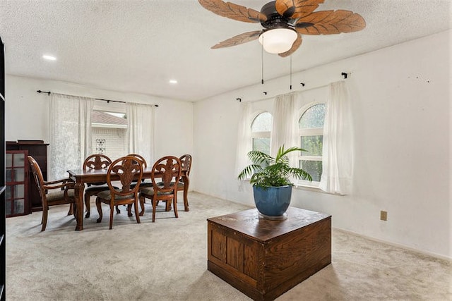 carpeted dining space with a textured ceiling and ceiling fan