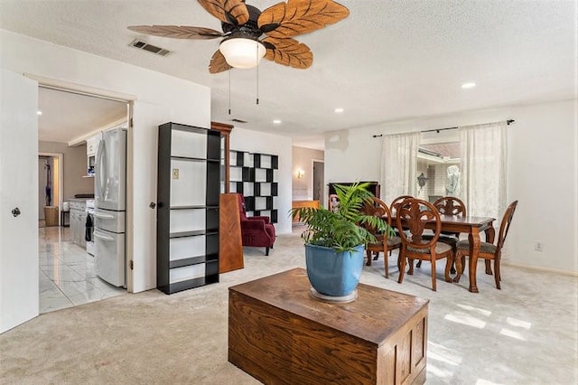 living room with a textured ceiling, light colored carpet, and ceiling fan