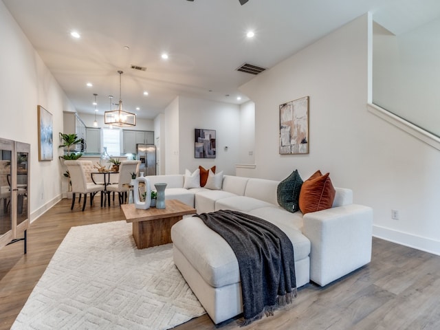 living room featuring a notable chandelier and light wood-type flooring