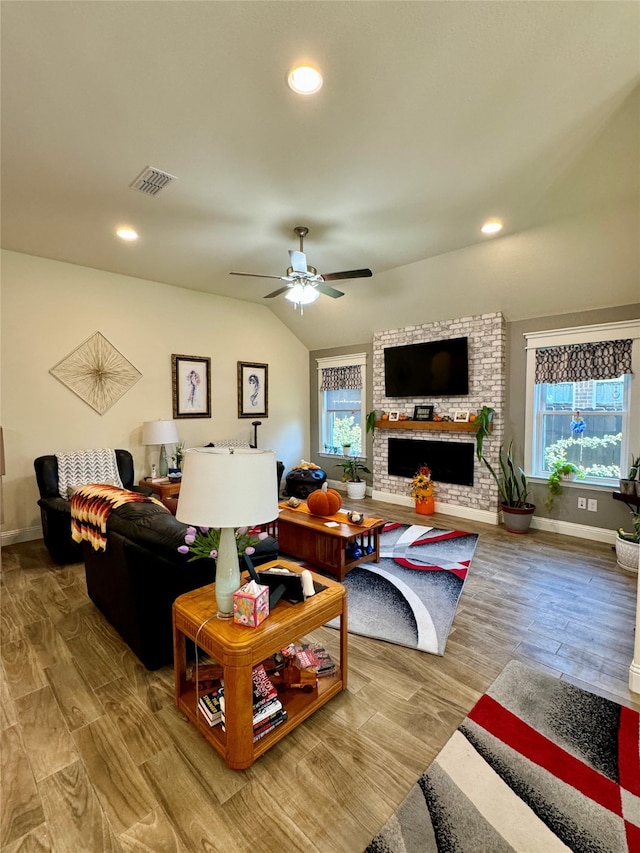 living room featuring hardwood / wood-style floors, a healthy amount of sunlight, a fireplace, and vaulted ceiling