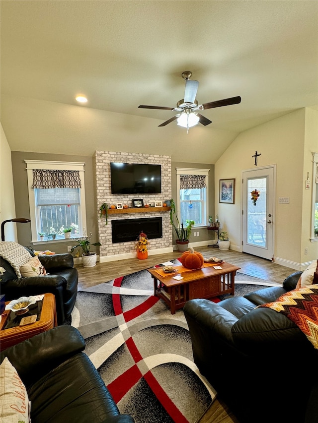 living room featuring ceiling fan, lofted ceiling, plenty of natural light, and a fireplace