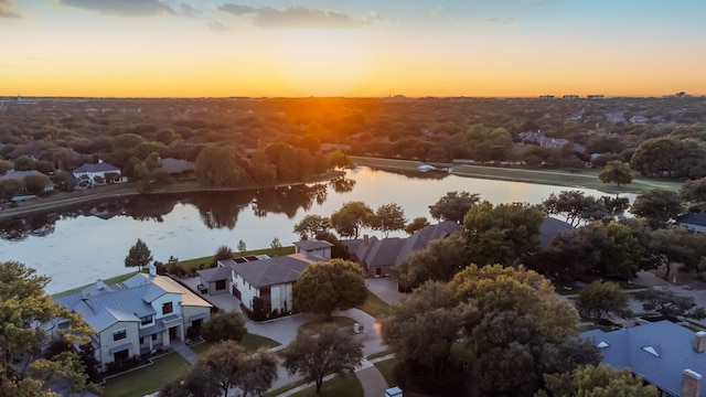 aerial view at dusk featuring a water view