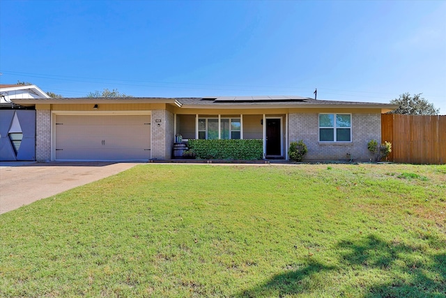 ranch-style house with a front yard, a garage, and solar panels