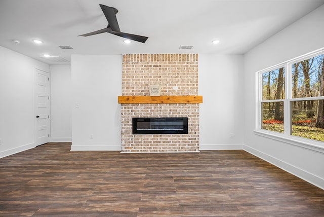 unfurnished living room featuring a fireplace, dark hardwood / wood-style floors, and ceiling fan