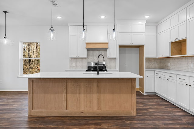 kitchen featuring white cabinets, a center island with sink, and sink