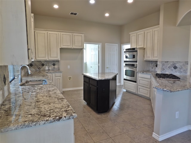 kitchen featuring tasteful backsplash, sink, a kitchen island, stainless steel appliances, and light stone counters