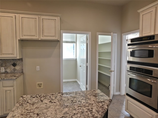 kitchen with cream cabinetry, light stone countertops, tasteful backsplash, and light tile patterned floors