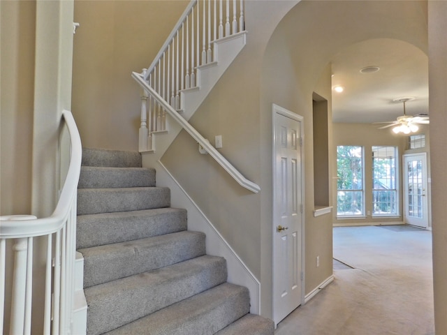 staircase with ceiling fan and carpet