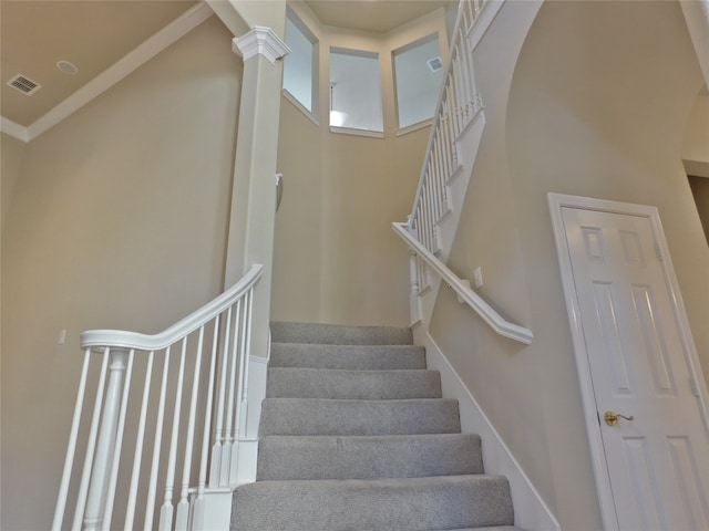 stairs with ornate columns and crown molding