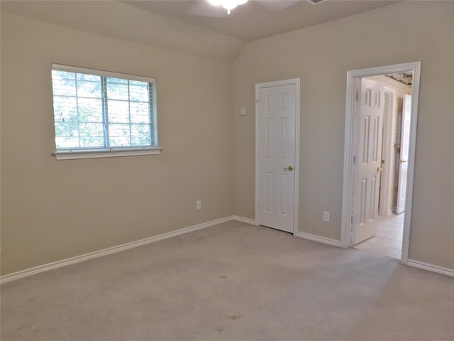 carpeted spare room featuring ceiling fan and vaulted ceiling