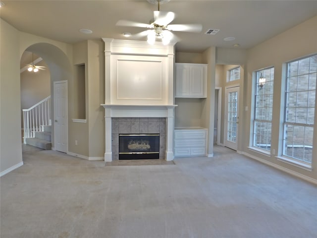 unfurnished living room with light colored carpet, a tile fireplace, and ceiling fan