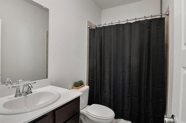 bathroom with walk in shower, vanity, and toilet