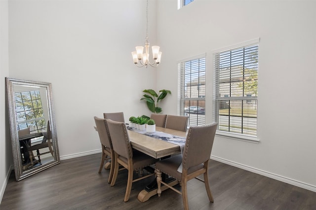 dining area with a high ceiling, plenty of natural light, dark hardwood / wood-style floors, and an inviting chandelier