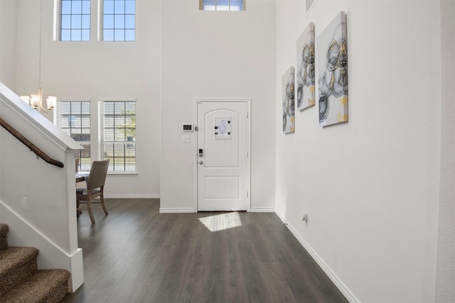 entryway with dark wood-type flooring, a towering ceiling, and a notable chandelier