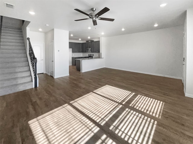 unfurnished living room featuring dark wood-type flooring and ceiling fan