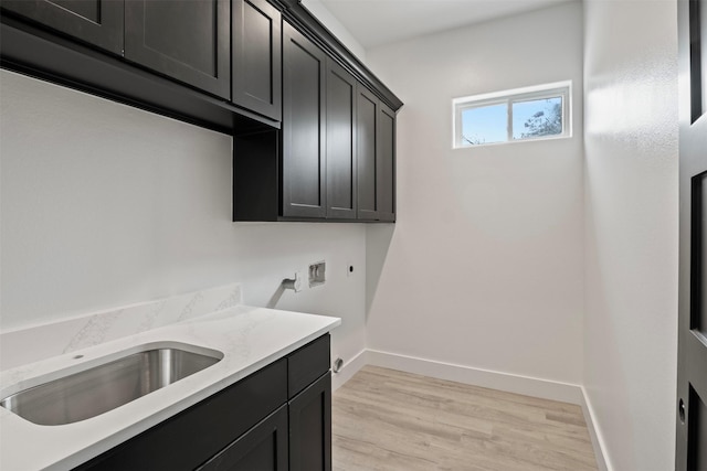 clothes washing area with electric dryer hookup, cabinets, sink, hookup for a washing machine, and light hardwood / wood-style flooring