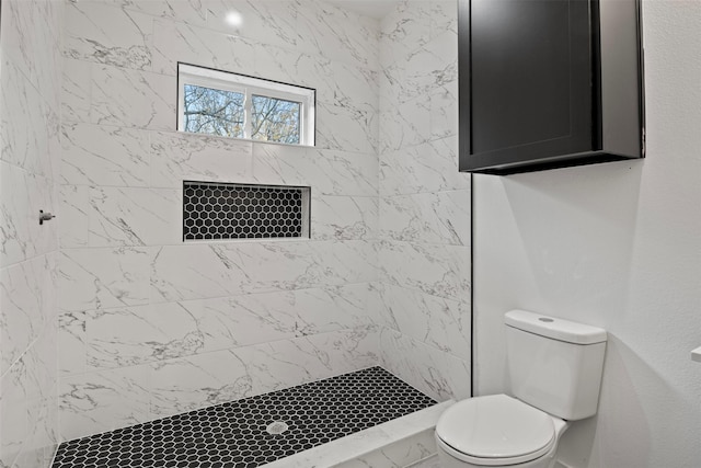 bathroom with a tile shower and toilet