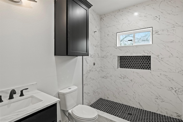 bathroom with vanity, toilet, and a tile shower