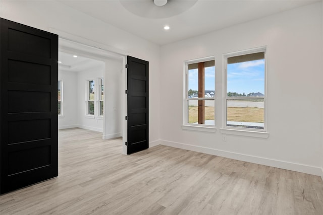 spare room with ceiling fan and light wood-type flooring