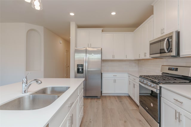 kitchen featuring backsplash, sink, light hardwood / wood-style flooring, appliances with stainless steel finishes, and white cabinetry