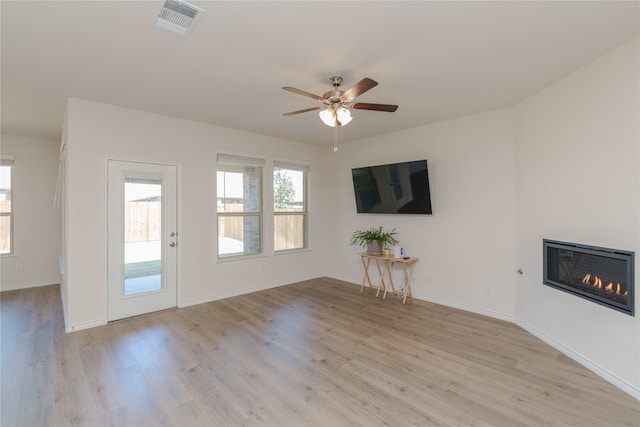 unfurnished living room with ceiling fan, a wealth of natural light, and light hardwood / wood-style flooring