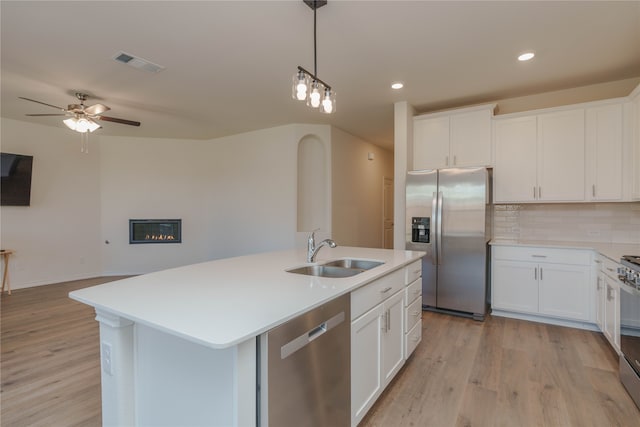 kitchen with appliances with stainless steel finishes, white cabinetry, a kitchen island with sink, and sink