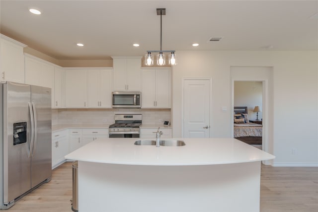 kitchen featuring white cabinets, stainless steel appliances, a center island with sink, and sink