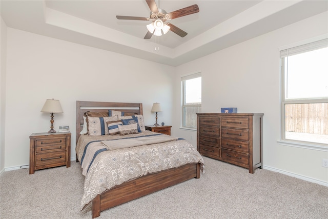 carpeted bedroom featuring ceiling fan and a raised ceiling