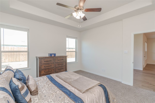 carpeted bedroom with a tray ceiling and ceiling fan