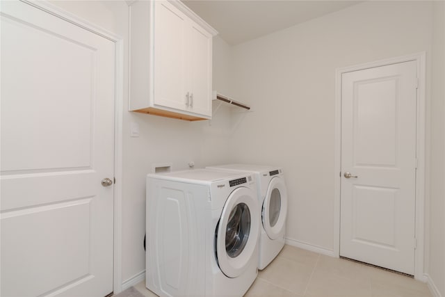 clothes washing area with cabinets, light tile patterned floors, and washer and dryer