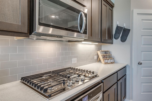 kitchen featuring light stone countertops, dark brown cabinetry, stainless steel appliances, and tasteful backsplash