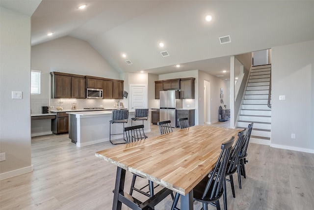 dining space with vaulted ceiling and light hardwood / wood-style floors