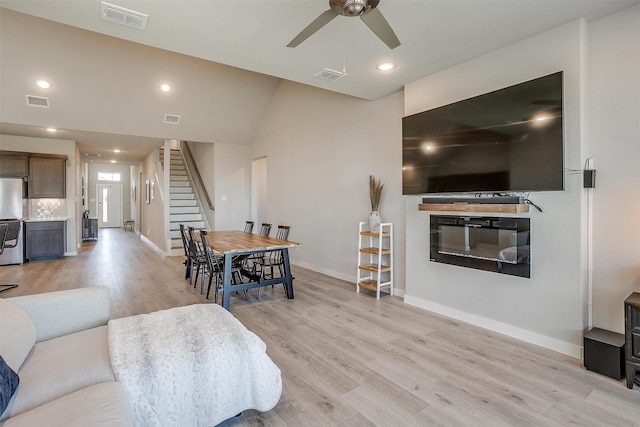 living room with ceiling fan, vaulted ceiling, and light hardwood / wood-style flooring