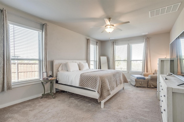 bedroom with light carpet, multiple windows, and ceiling fan