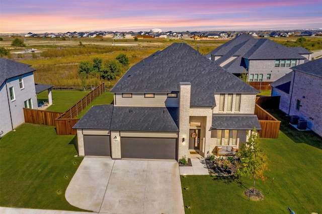 view of front of home featuring fence, driveway, roof with shingles, a front lawn, and a residential view